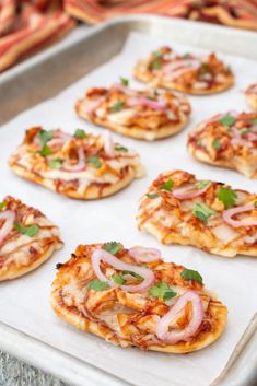 small pizzas with onions and cheese on a baking sheet