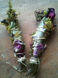 two bundles of dried flowers tied together on a wooden table with twine and string