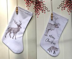 two christmas stockings hanging from hooks with deer and reindeer designs on them next to red berries