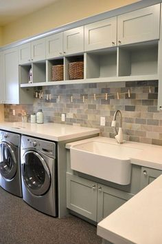 a washer and dryer in a room with cabinets on either side of the sink