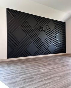 an empty room with wood flooring and black art work on the wall behind it