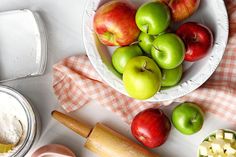 apples and other ingredients are in bowls on a table