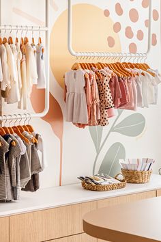 the baby clothes are hanging on racks in front of a wall with polka dot designs