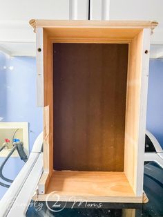 an empty wooden box sitting on top of a table next to a white wall and blue walls