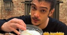 a man holding a bowl filled with food next to a plate full of pasta noodles