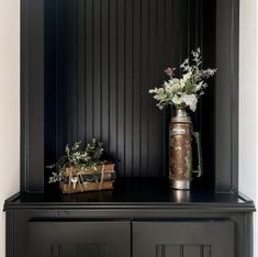 a vase with flowers sitting on top of a black cabinet