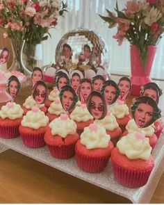 cupcakes with pictures of people on them are displayed in front of vases