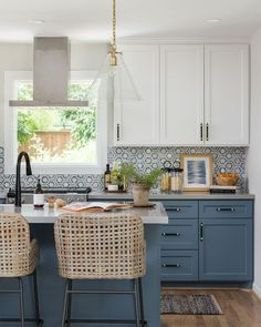 two wicker chairs sit at an island in the middle of a kitchen with blue cabinets