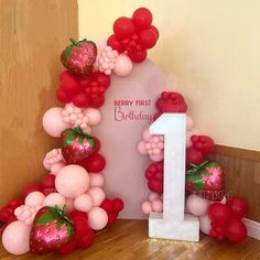 the number one balloon arch is decorated with strawberries and balloons for a first birthday