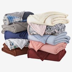 folded towels and blankets stacked on top of each other in various colors, patterns and sizes