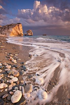 the beach is full of rocks and waves coming in to shore as the sun sets