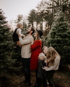 a family with two children standing in front of christmas trees at the tree farm during an extended family photo session