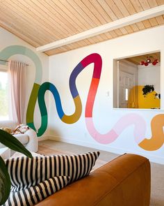 a living room filled with furniture and colorful wall art on the walls above it's windows