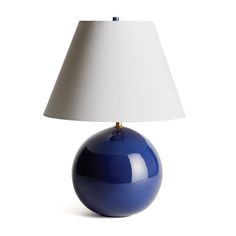 a blue lamp sitting on top of a table next to a white lampshade