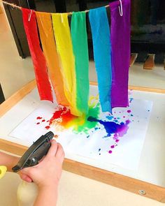 someone is using scissors to paint the rainbows on paper with colored watercolors