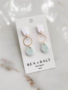 the sea and salt earrings are on display in front of a white card with a gold hoop