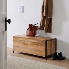 a coat rack with shoes on it in front of a white wall and wooden floor