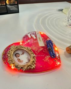 a red heart shaped frame sitting on top of a table next to a teddy bear