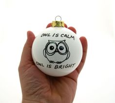 a hand holding a white ornament with an owl on it