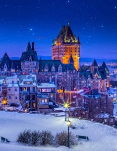 the city is lit up at night with snow on the ground and stars in the sky