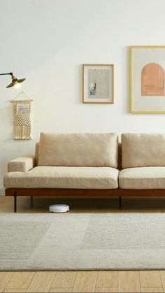 a living room with two couches and pictures on the wall above them, along with a rug