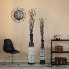 three black and white vases sitting on top of a wooden floor next to a chair