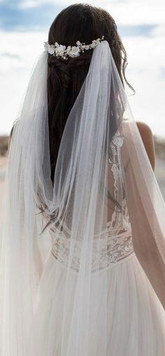 the back of a bride's wedding dress with her veil draped over her head