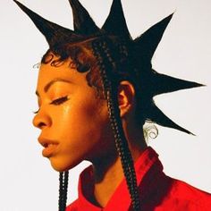 a woman with black spikes on her head and braids in front of her face