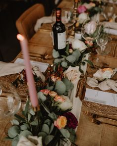 the table is set with flowers, candles and wine bottles for dinner guests to enjoy