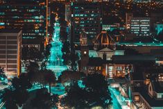 an aerial view of a city at night with buildings lit up in blue and green