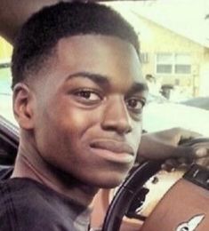 a young man holding a bag in his hand while sitting in the driver's seat of a car