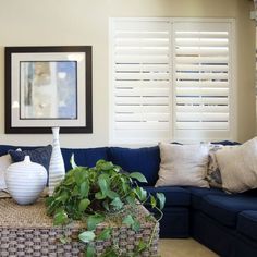 a living room with blue couches and white vases