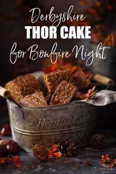 a metal bowl filled with brownies next to pine cones and cinnamons on a table