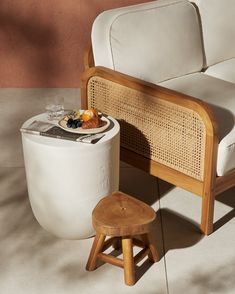 a white couch sitting next to a table with drinks on it and a small stool in front of it