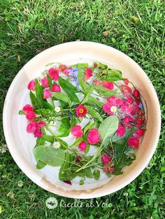 a bowl filled with flowers on top of green grass