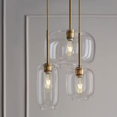 three clear glass pendant lights hanging from a ceiling fixture in a room with white walls