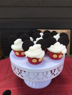 cupcakes with white frosting and mickey mouse decorations on a cake platter