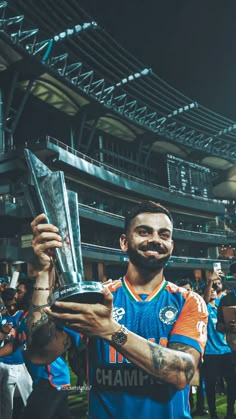 a man holding up a trophy while standing in front of a crowd at a soccer game