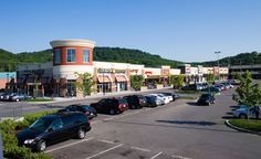 an empty parking lot with cars parked in front of shops and stores on the side