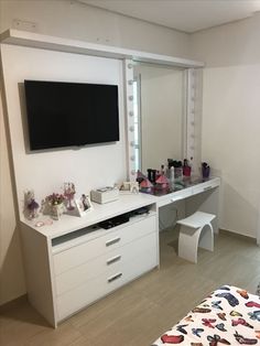 a bedroom with white furniture and a flat screen tv mounted on the wall above it