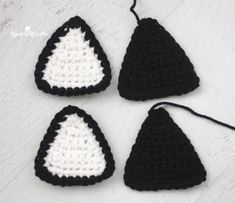 three crocheted triangle ornaments are shown on a white surface with black and white trim