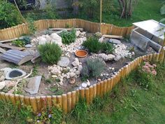 an outdoor garden with rocks and plants in the center, surrounded by wooden fence posts