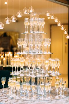 a table topped with lots of wine glasses next to a chandelier filled with champagne