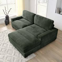 a large green couch sitting on top of a wooden floor