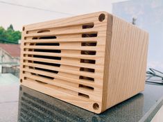 a wooden speaker sitting on top of a counter next to a building and trees in the background