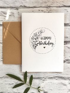 a card with the words happy birthday written in black on it next to a brown envelope