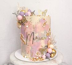 there is a pink cake with gold decorations on the top and bottom, sitting on a marble stand