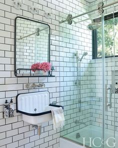 a white tiled bathroom with a sink, mirror and shower