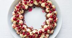 a white plate topped with a cake covered in cranberries and cream frosting