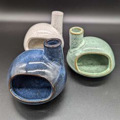 three ceramic vases sitting next to each other on top of a gray countertop